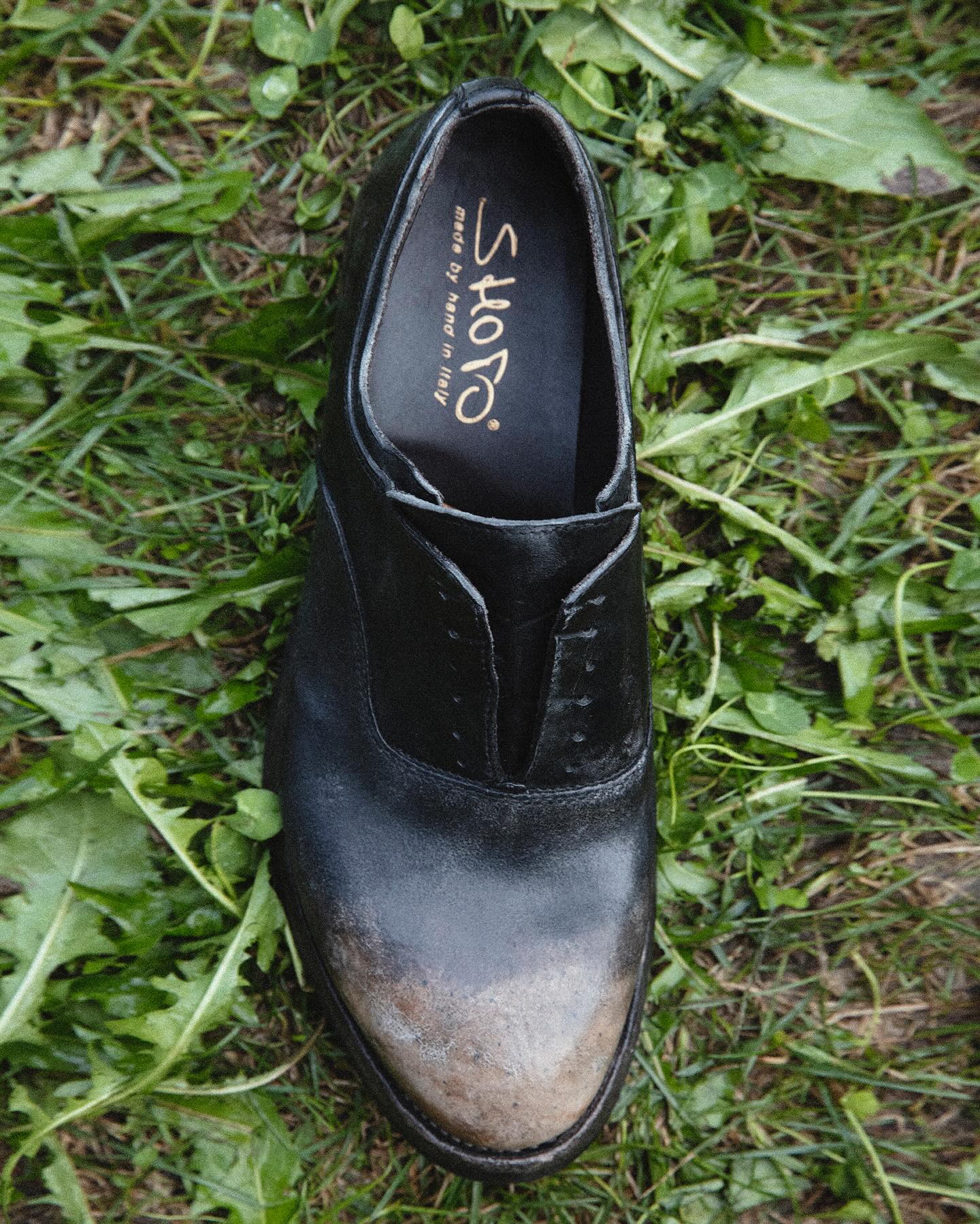Shoto black lace-less shoe photographed on grass