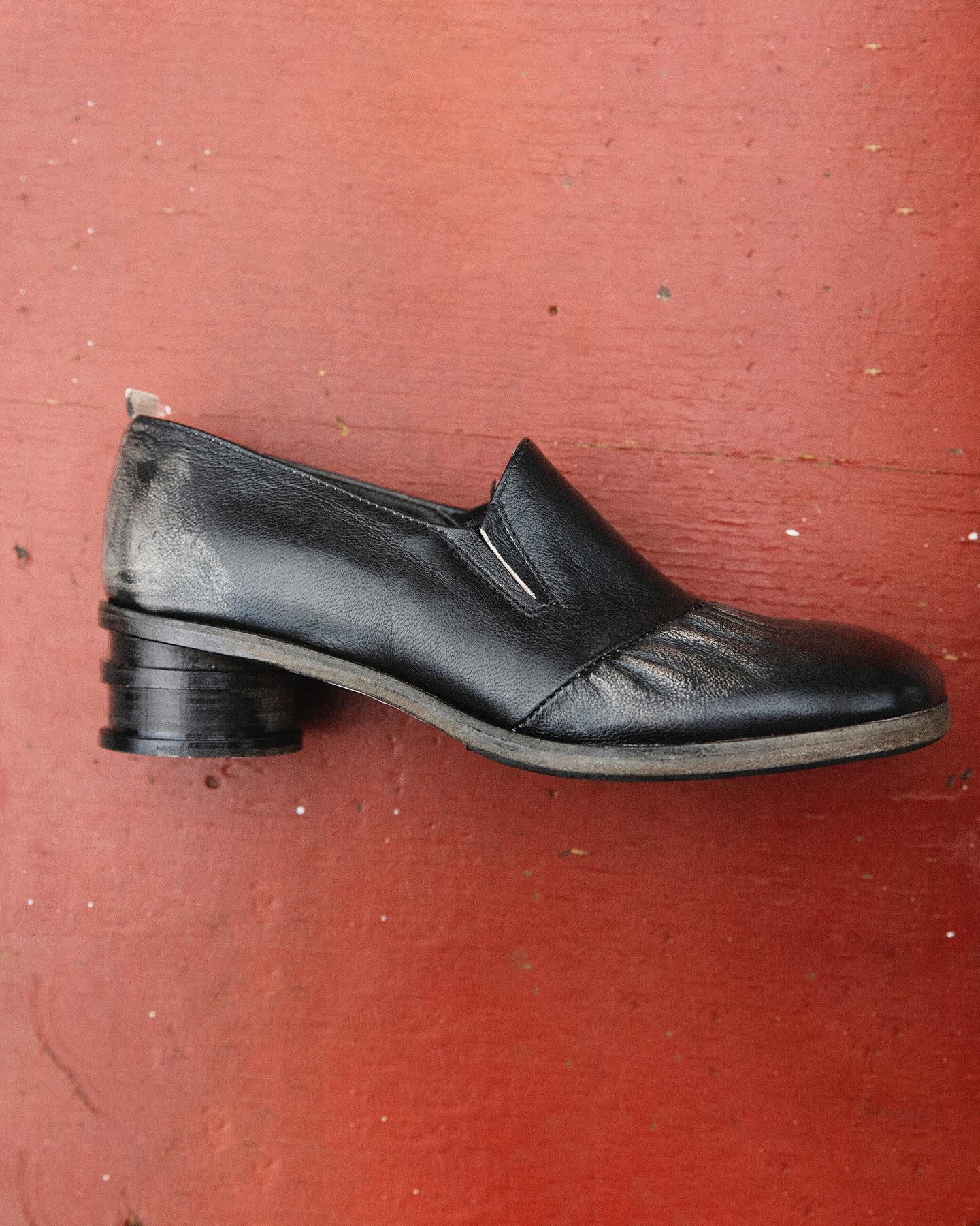 Shoto black low heel leather shoe on a red floor